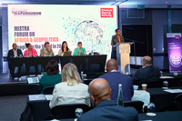 A conference panel sits on a stage in a hotel meeting room, with speakers seated at a table and one speaker standing at a podium. The screen behind them displays the MISTRA Forum on Africa & Geopolitics and Friedrich-Ebert-Stiftung logos. Attendees sit at tables facing the stage.
